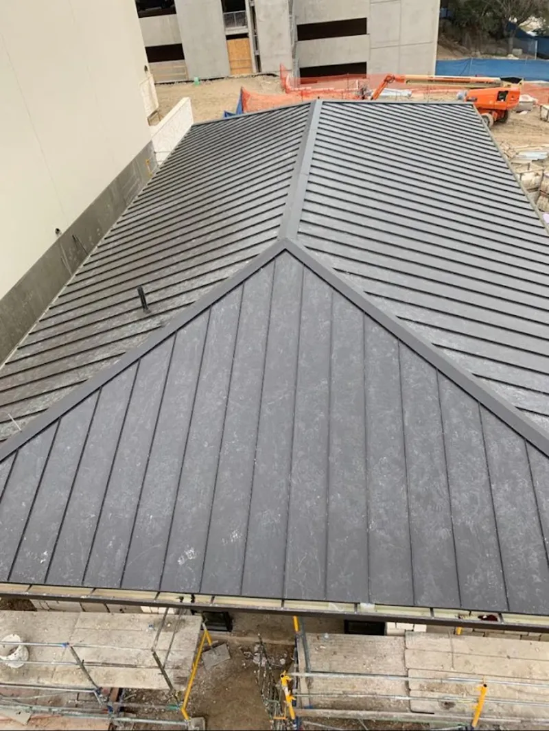 Commercial metal roof construction with crane equipment in West Greenwich